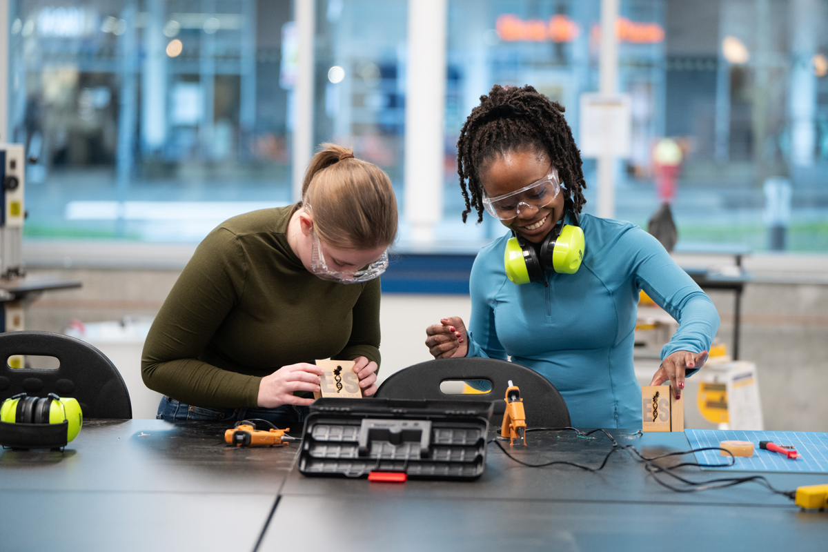 Two students working on a device in a maker space