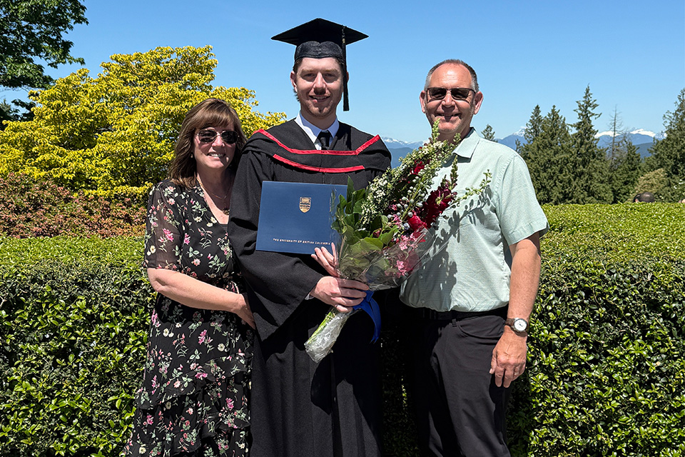 A UBC graduate surrounded on both sides by family members
