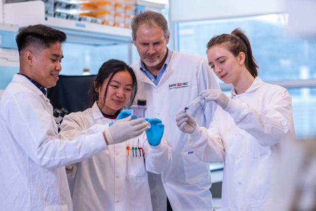 A group of students and a doctor work together in a lab.