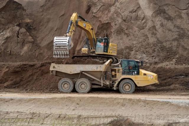 An excavator shovels dirt into a truck.
