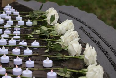 White roses and tea lights sit on the 14 Not Forgotten memorial