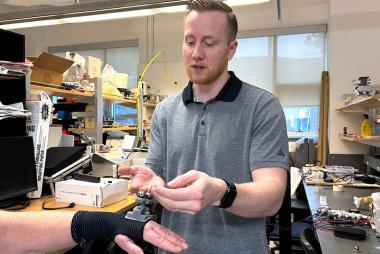 Dr. Dylan Goode demonstrates the tremor suppression device