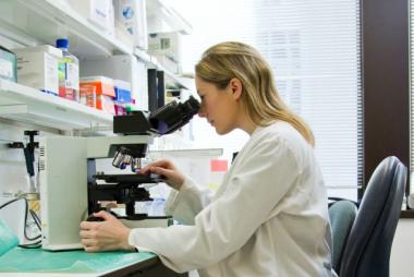Woman looking through lab microscope