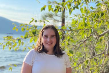 An female engineering student by a tree and a river