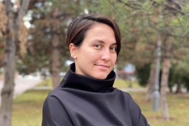 UBC MEL student Ezgi Yuruk smiles at the camera. She is centred with trees behind her.