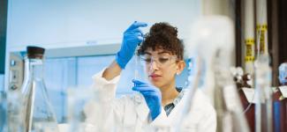 Student in a lab holding a mini Erlenmeyer flask.
