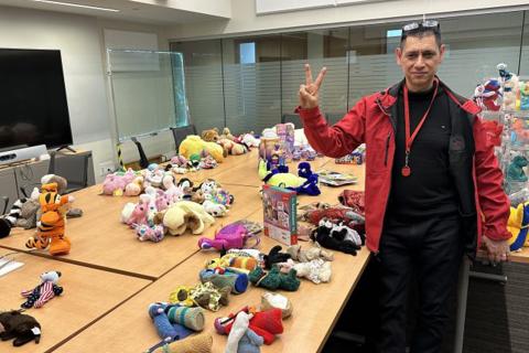 Dr. Ray Taheri stands next to tables full of stuffed toys