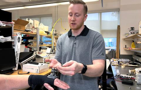 Dr. Dylan Goode demonstrates the tremor suppression device